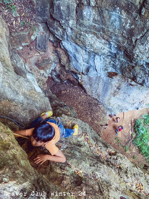 A child climbing a rock face with a rope and harness