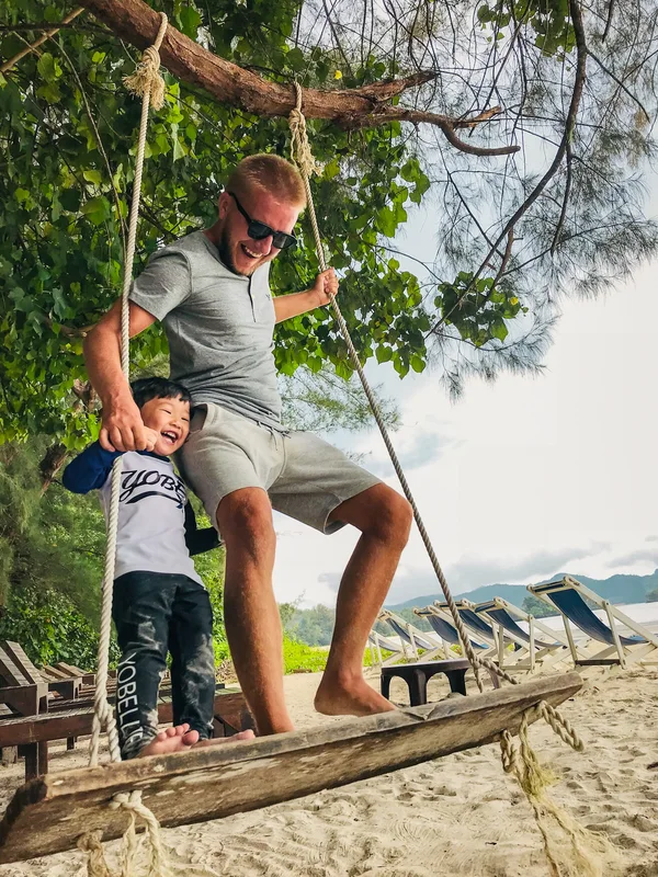 A father and young child balancing together on a suspended wooden platform