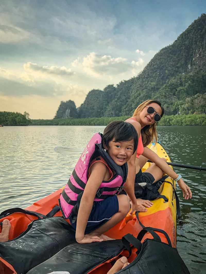 An adult and child wearing life jackets in a kayak beneath limestone hills