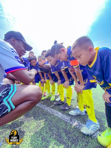 Fury Hawks players listening together to an adult beside the pitch