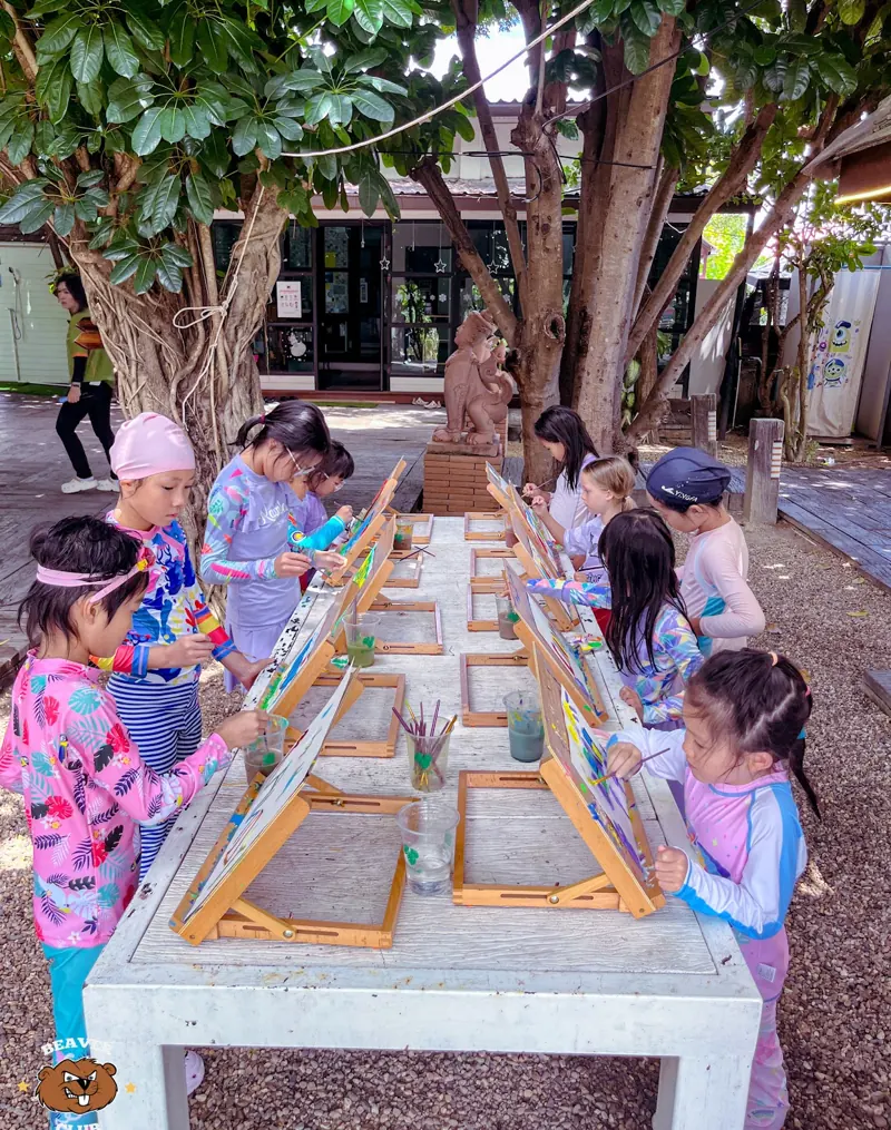 Children painting together around an outdoor table at Beaver Club