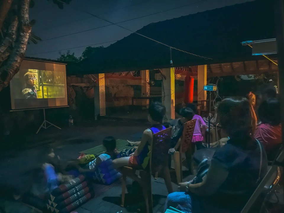 Families watching a film on an outdoor projector screen at Beaver Club