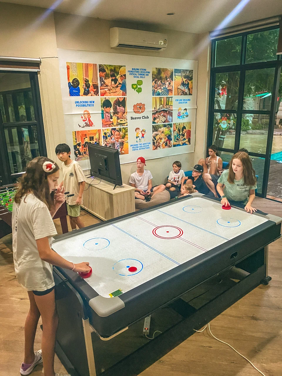 Children playing air hockey together in the Beaver Club games room