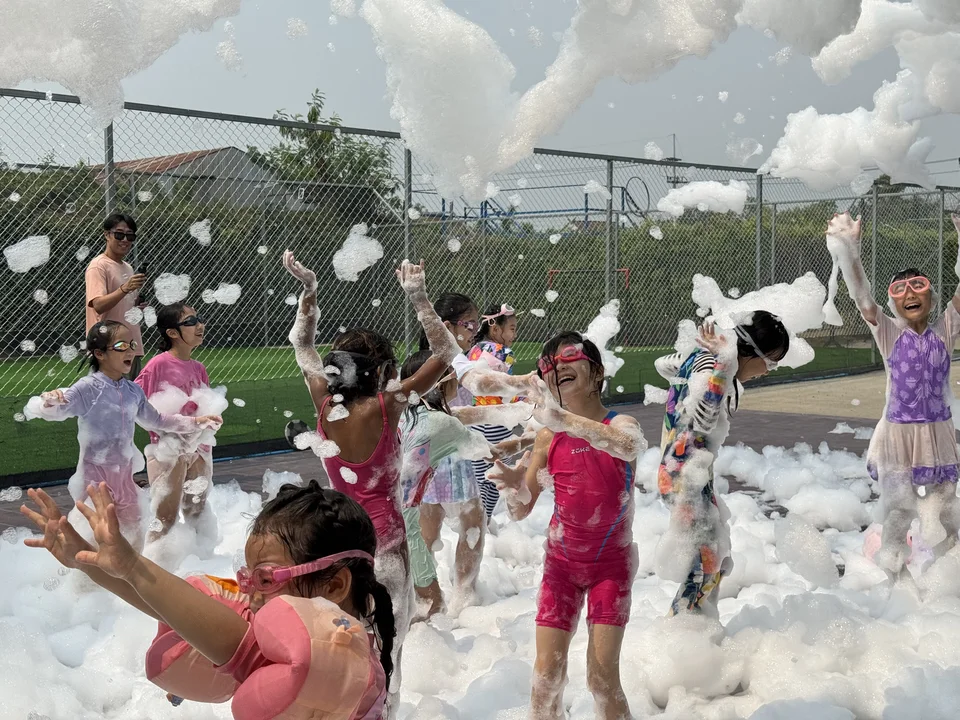 Children wearing goggles and tossing foam into the air on the outdoor sports area