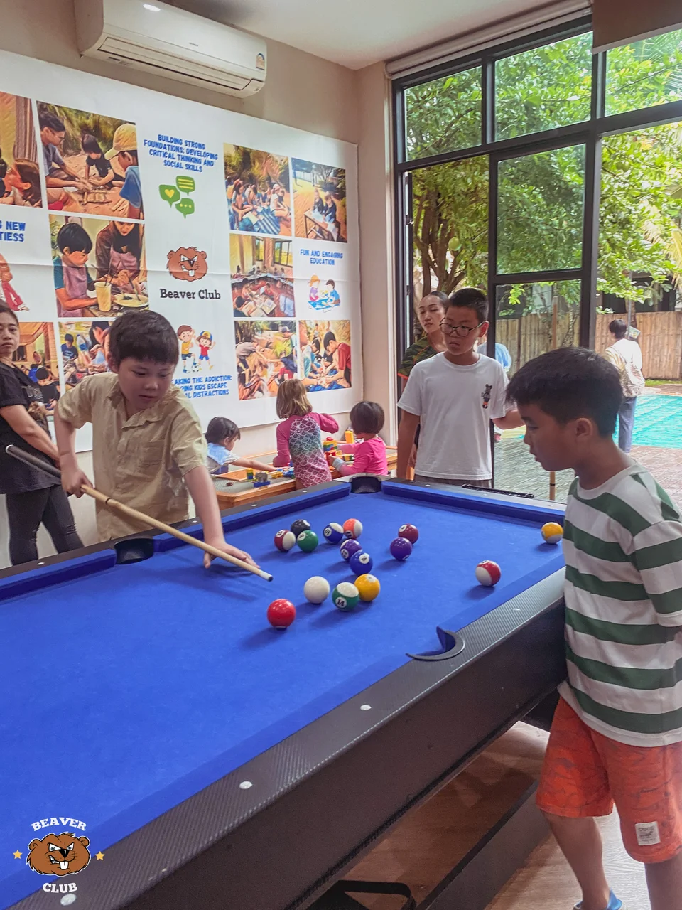 Children playing pool together around a blue pool table in the games room