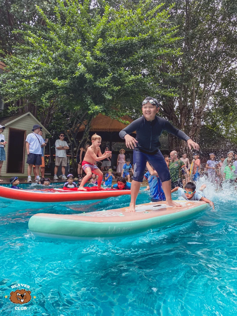 Children balancing on paddleboards and playing together in the Beaver Club pool