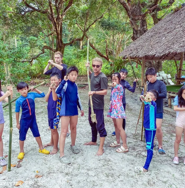 Children holding fishing rods beside a shelter on the island