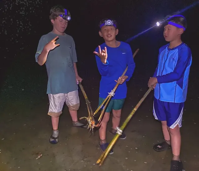 Children holding fishing rods and their catch during a night fishing trip