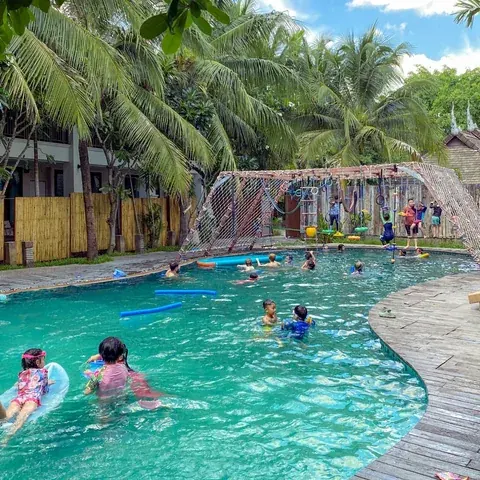 Children and families swimming in the palm-lined Beaver Club pool
