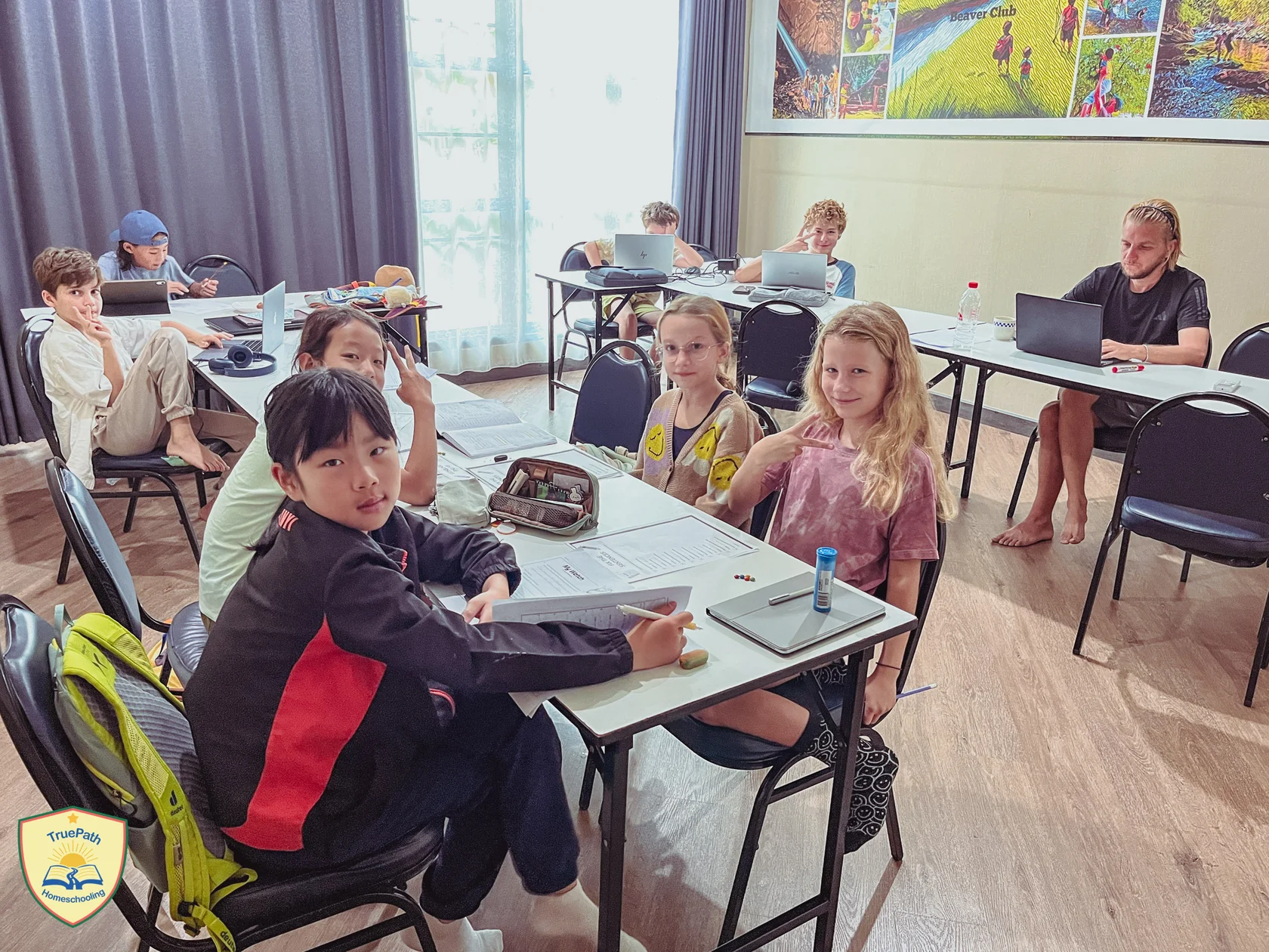 Children learning together at classroom tables, with an adult guiding their study at TruePath