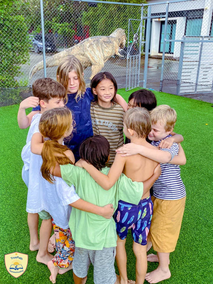 Children gathering for a group hug beside the sports field