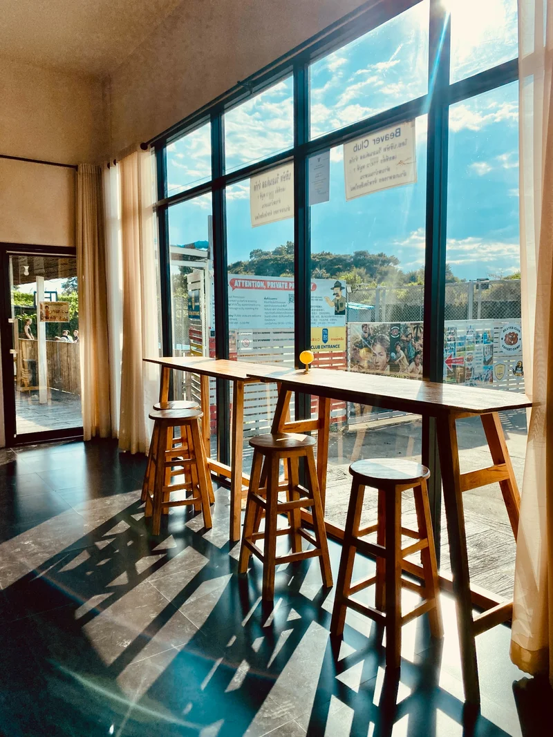 A long indoor work counter and stools beside bright windows