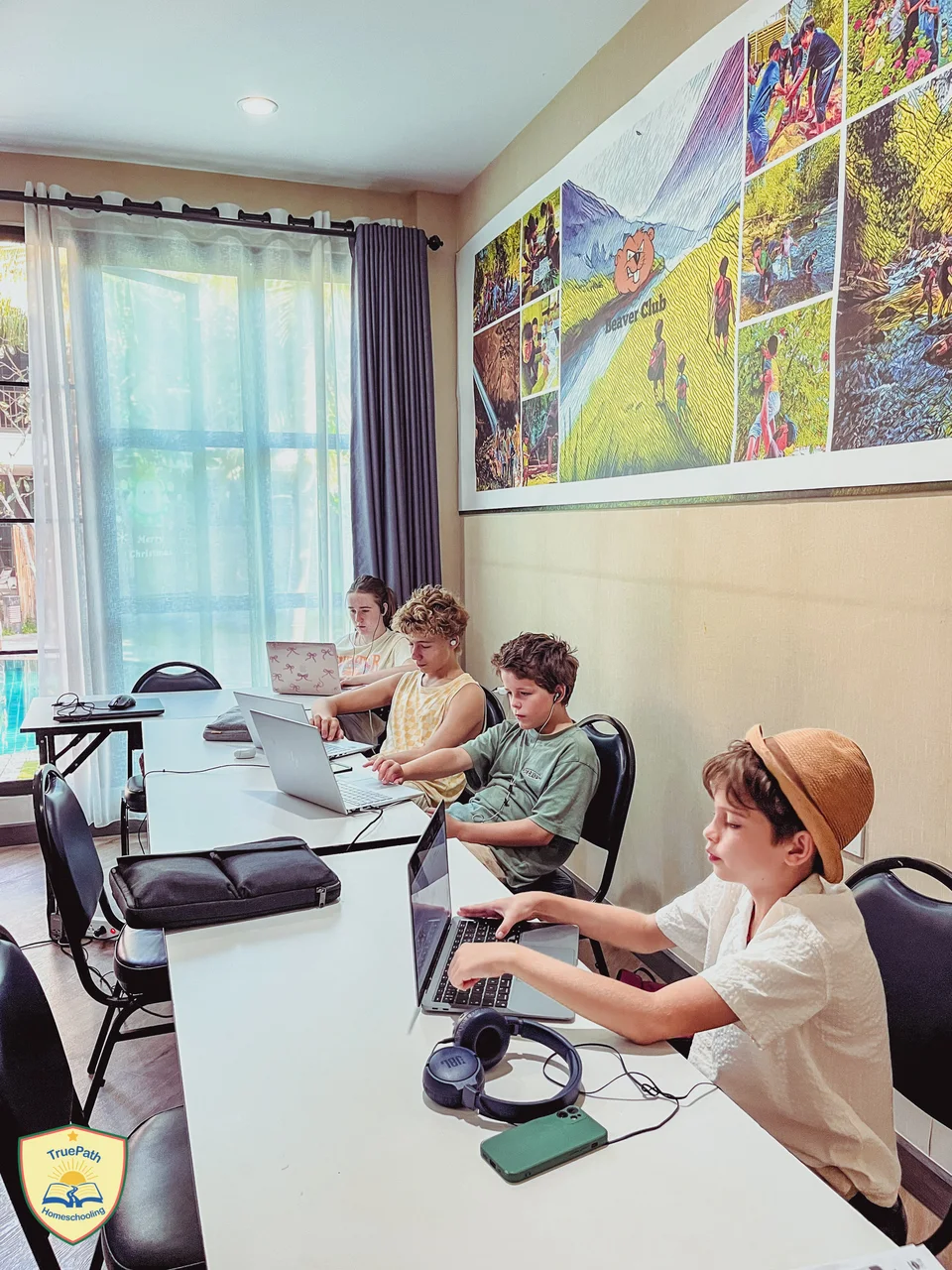 Children working on their individual lessons at classroom tables with laptops and headphones