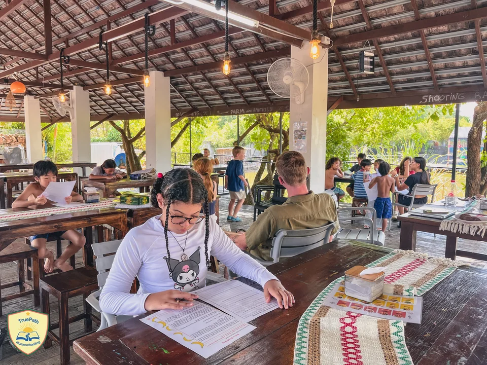 Children working on their lessons at tables in the open-air learning space