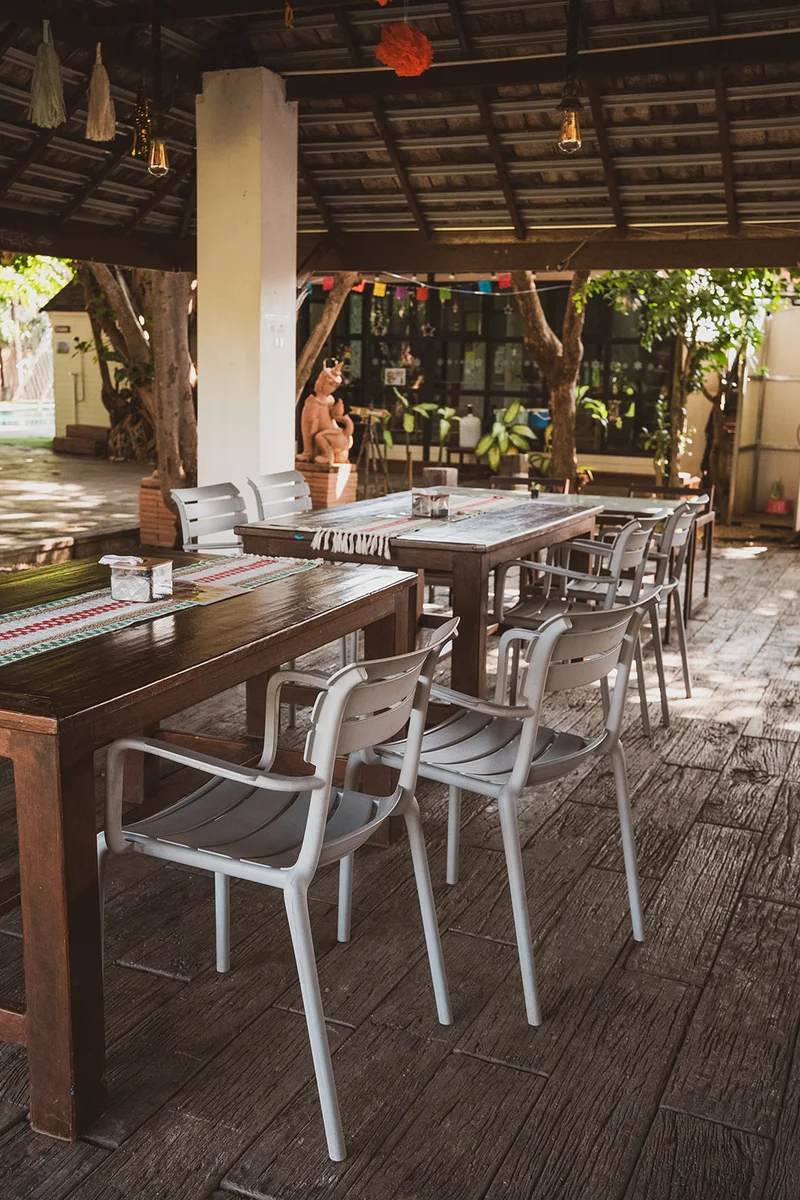 Tables and chairs beneath the open-air pavilion roof beside the garden