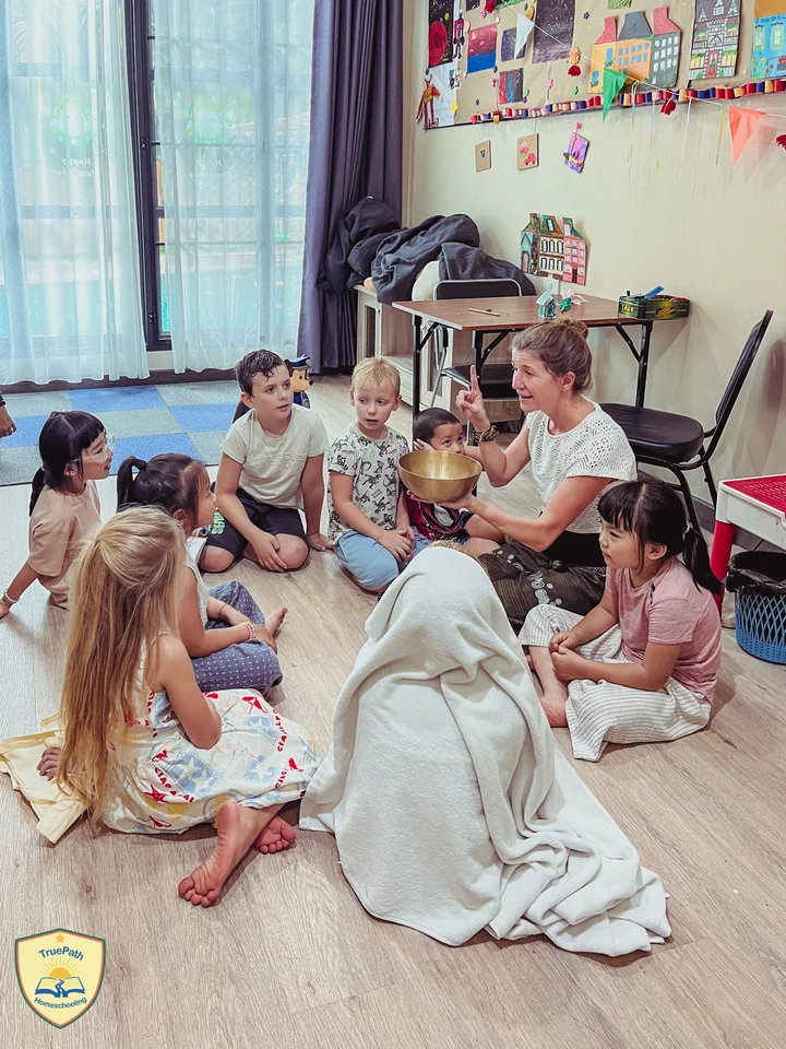An adult joining a group of children sitting together on the classroom floor