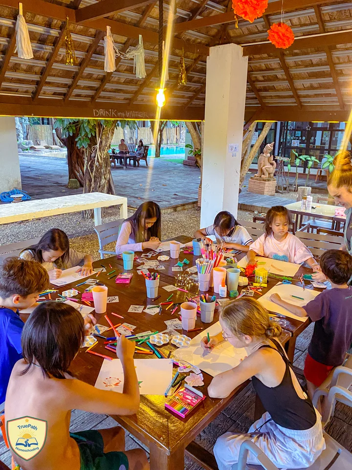 Children painting and making colourful artwork around a table