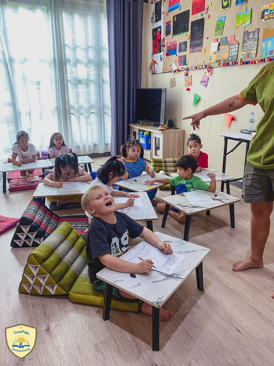 Younger children working with pencils and paper in the TruePath classroom