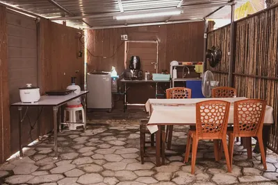 Covered shared kitchen with cooking equipment and a dining table